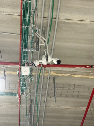 זוג מצלמות לבנות המותקנות מתחת לתקרה ליד תעלות כבלים