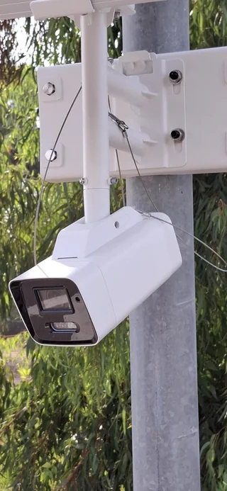 מצלמת אבטחה לבנה וקופסת חיבורים על עמוד
